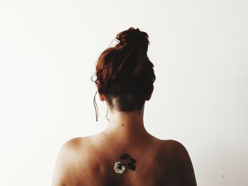 Rear view of shirtless woman with plants on back against white background