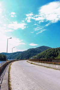 Empty road by mountains against sky