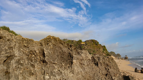 Rock formation on beach against sky