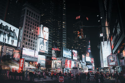 People on illuminated street amidst buildings in city at night