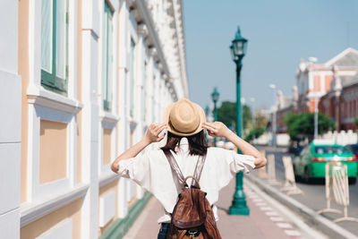 Rear view of woman standing on street against buildings in city