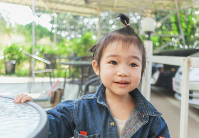 Close-up of cute baby girl sitting on chair outdoors