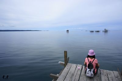 Rear view of woman sitting on pier