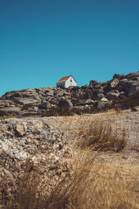 Low angle view of rocks on field against clear blue sky