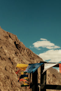 Prayer flags against blue sky and arid mountain landscape.