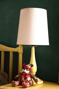 Close-up of illuminated lamp on table against wall at home