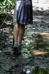 Low section of woman walking on muddy land in forest