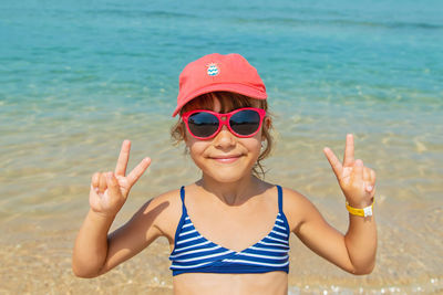 Portrait of smiling young woman wearing sunglasses against sea