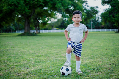 Full length of boy playing with ball on grass