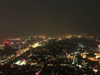 High angle view of illuminated city buildings against sky at night