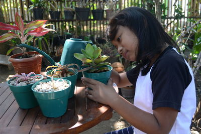 Side view of girl holding potted plant