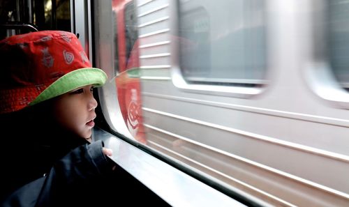 Close-up of girl looking through window in train