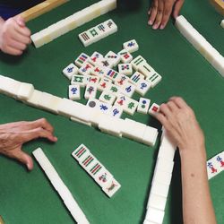 Cropped image of people playing mahjong on table