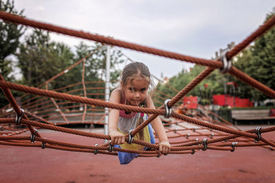 Full length of girl playing on rope in playground