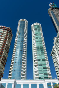 Low angle view of modern buildings against clear blue sky