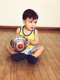 Portrait of boy playing with toy on hardwood floor at home