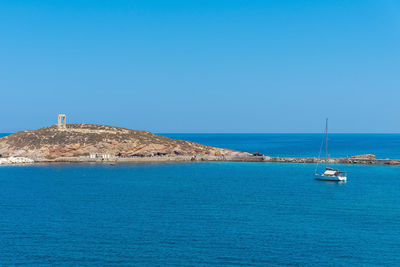 Sailboat in sea against clear blue sky