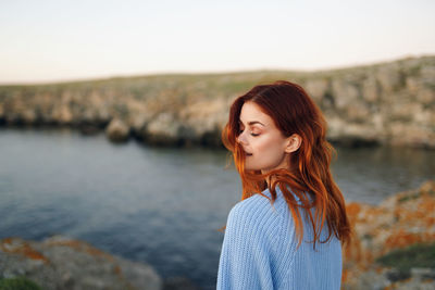 Portrait of beautiful woman standing against water