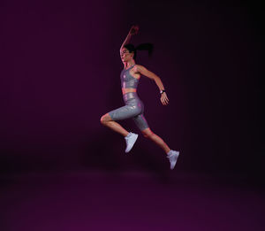 Full length of woman exercising against black background