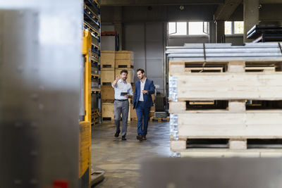 Businessman and colleague inspecting warehouse while walking at factory