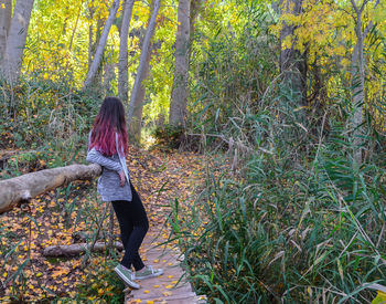 Woman standing by plants in forest