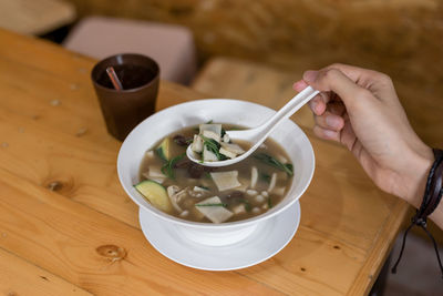 Cropped hand having soup served at table