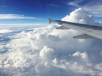 Cropped image of airplane wing in cloudy sky