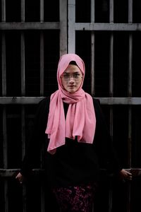 Portrait of young woman standing against brick wall