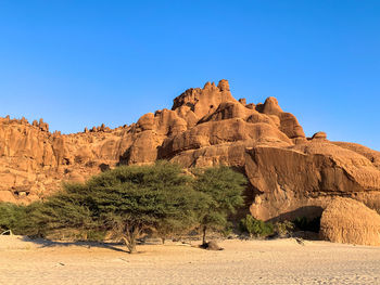 Rock formations on landscape against clear blue sky