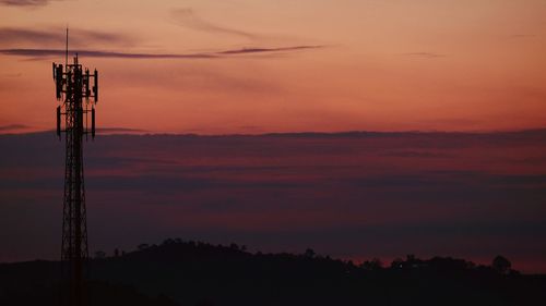 Silhouette of electricity pylon against sky during sunset