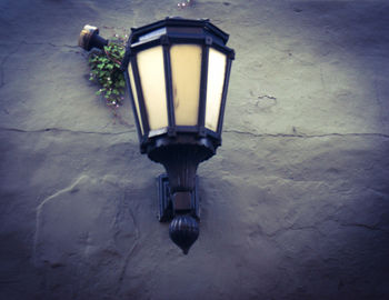 Low angle view of illuminated lamp on wall