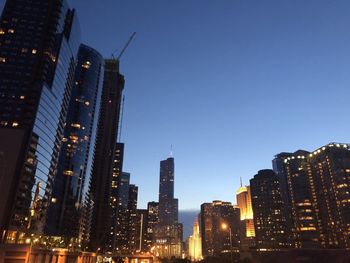 Illuminated buildings in city against sky at dusk