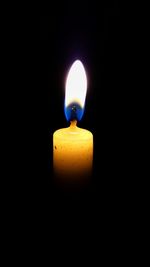 Close-up of lit candle in dark room