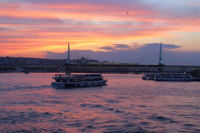 View of suspension bridge over river at sunset