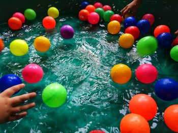 Cropped hands of children holding balls in wading pool