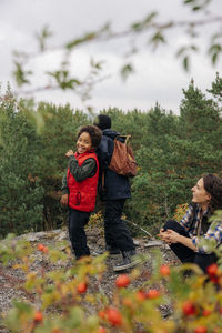 Smiling woman talking to happy son during vacation in forest