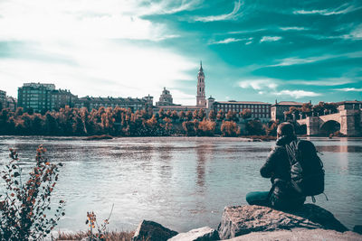 Rear view of woman looking at river against sky