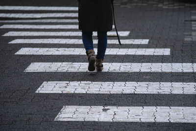 Low section of woman crossing road