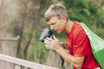 Man looking at camera while standing against railing