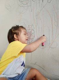 Side view of cute girl against wall