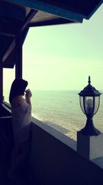 Rear view of man standing by sea against sky