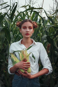 A beautiful girl with two bagels of hair on her head in a cornfield. a girl in a white shirt