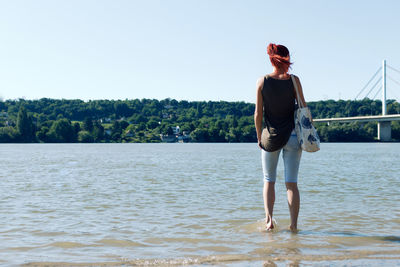 Rear view of a woman standing in the water during summer day. copy space.