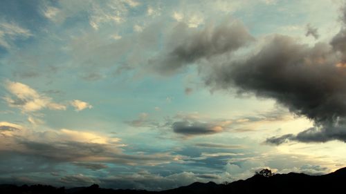 Silhouette of mountain range against cloudy sky