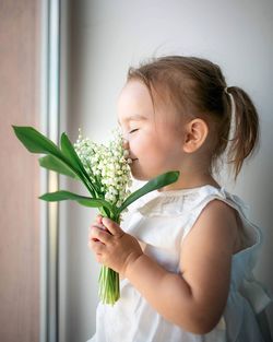 Cute girl holding flower at home