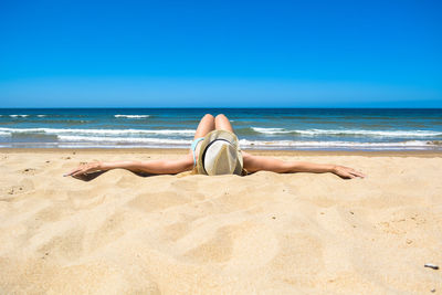 Rear view of woman on beach against blue sky