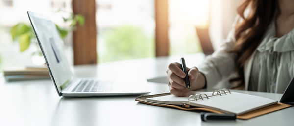 Midsection of woman using laptop on table