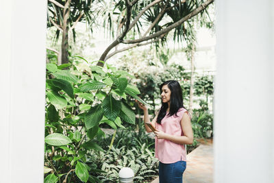 Young woman standing against plants