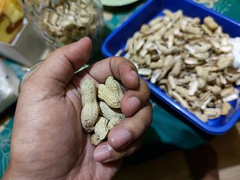 High angle view of person holding roasted peanuts on table