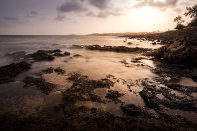 Scenic view of coast against sky during sunset